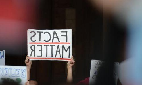 Hands holding up a sign that reads facts matter